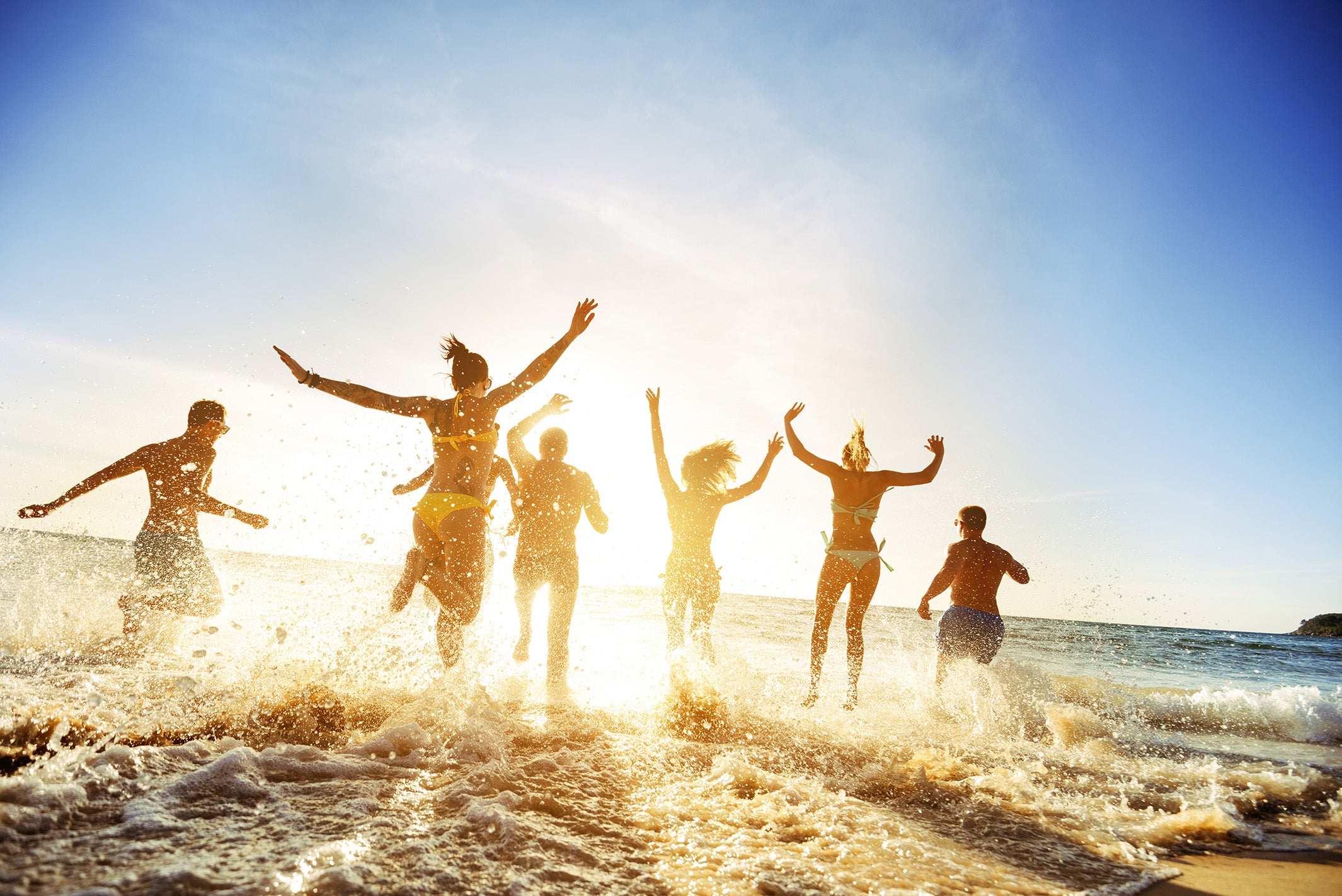 Group of friends running into the ocean at sunrise - Moxxie Motivational wristbands make the perfect gift for men and women.